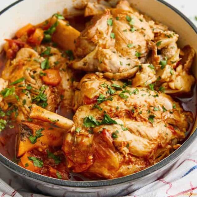 Stew chicken cooked in flavorful tomato sauce with herbs, served in a black skillet with fresh parsley garnish. Perfect for healthy, hearty meals and meal prep.