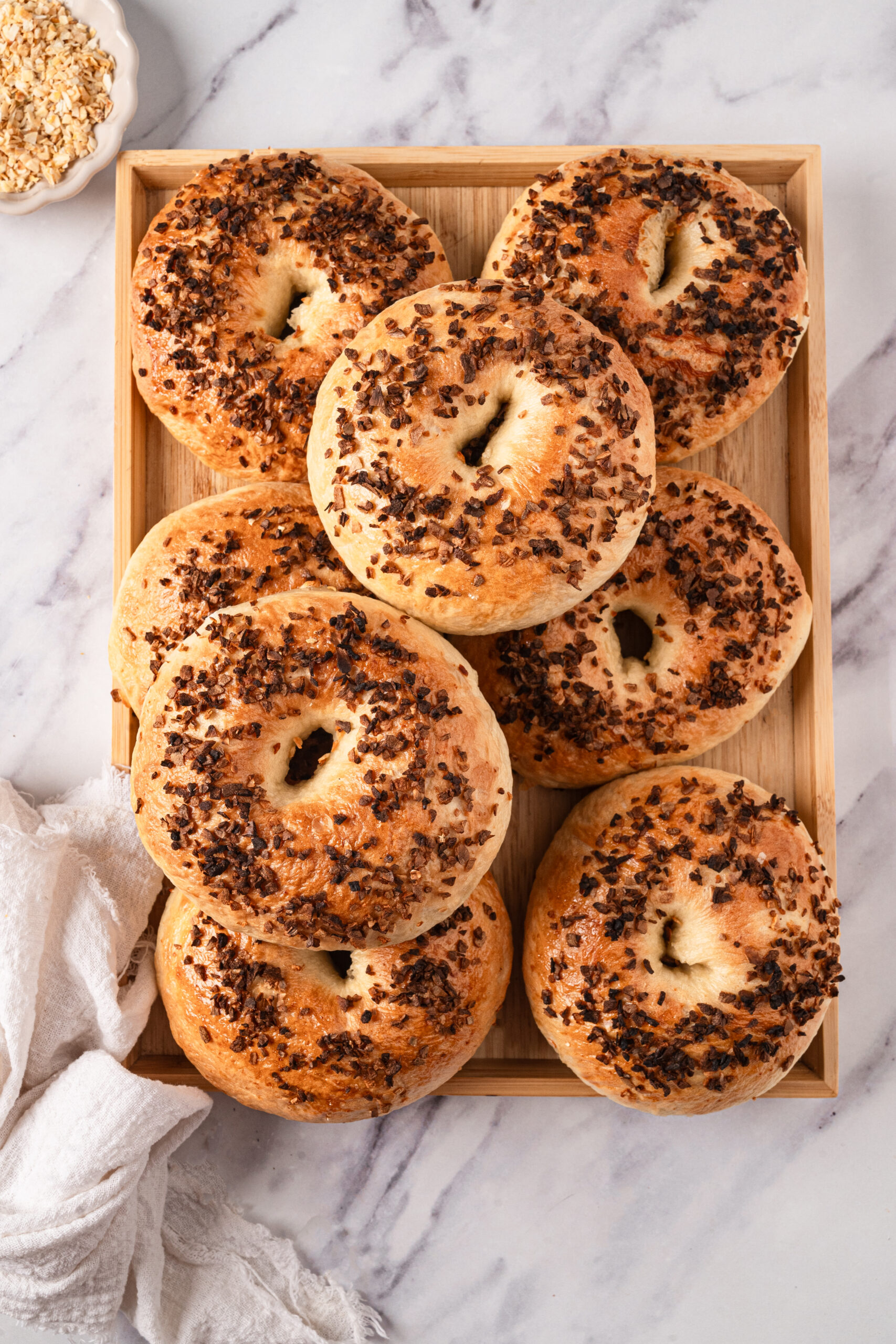 Golden brown bagels topped with chocolate chips on a wooden tray in a breakfast setting.