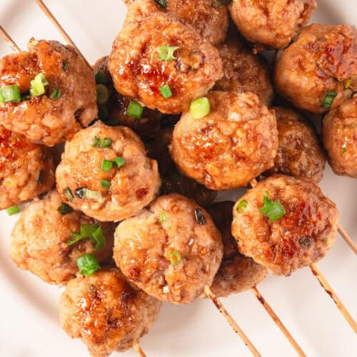 Savory Asian-style chicken meatballs on skewers garnished with chopped green onions, perfect for healthy meal ideas and nutritious recipes from Food Faith Fitness.