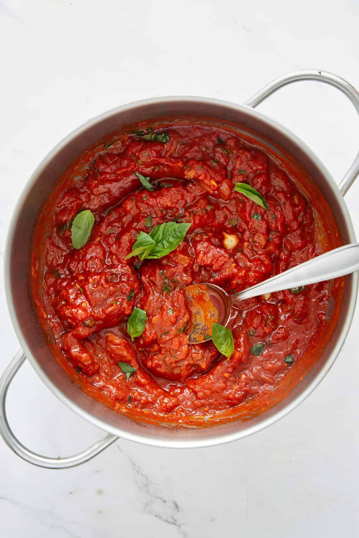 Rich homemade marinara sauce with fresh basil in a stainless steel pot. Perfect for healthy meal prepping, pasta, or gluten-free recipes on Food Faith Fitness.