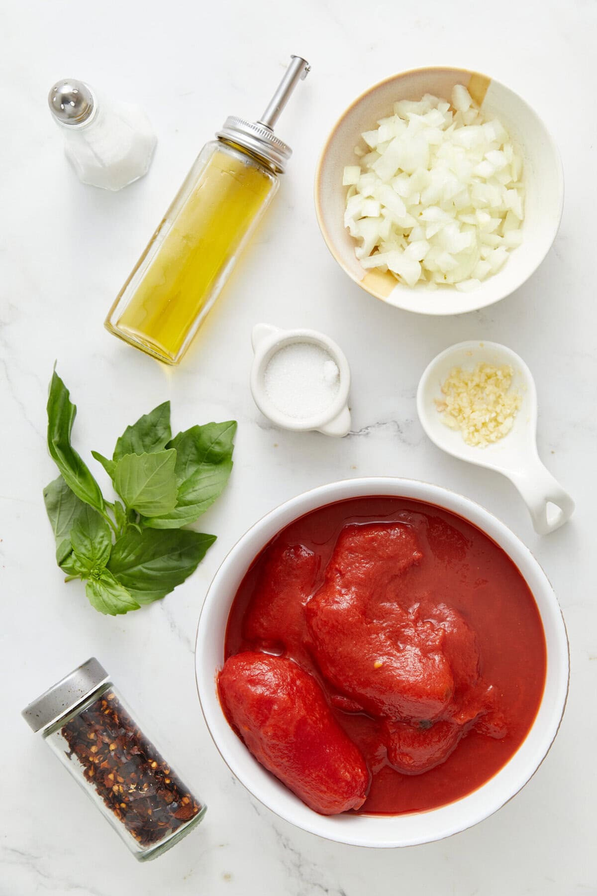 Fresh ingredients for homemade spaghetti Bolognese, including ground beef, chopped onions, garlic, herbs, and spices on a white marble surface. Perfect for healthy meal prep and Italian cuisine lovers.