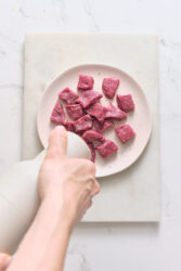 Seasoning garlic butter steak bites with salt and pepper.