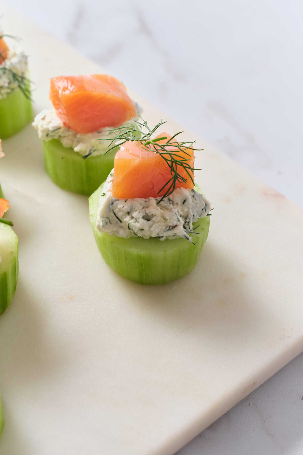 Fresh cucumber bites topped with herbed cream cheese, smoked salmon, and dill, perfect for healthy snacking or appetizers.