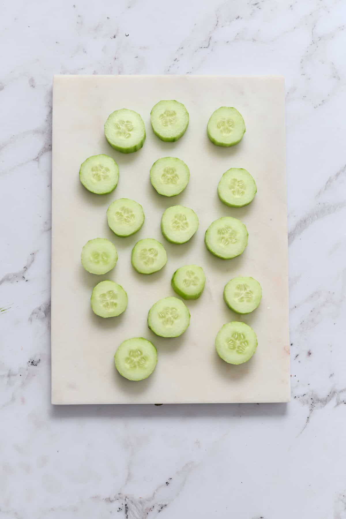 Fresh cucumber slices on a white cutting board for healthy eating and nutritious snack ideas from Food Faith Fitness.