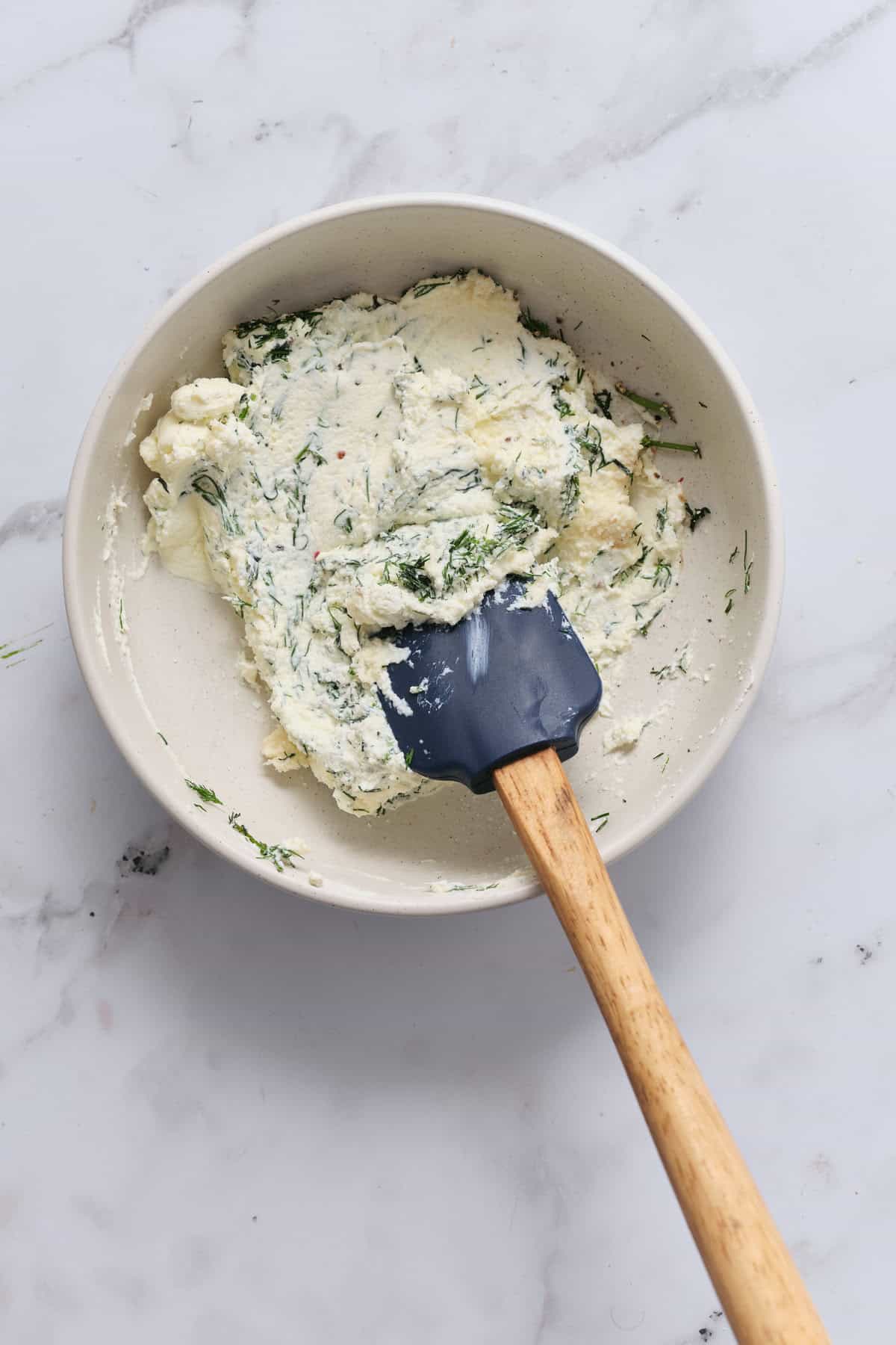 Cream cheese herb spread with dill and garlic on a white bowl, ready for spreading or serving.
