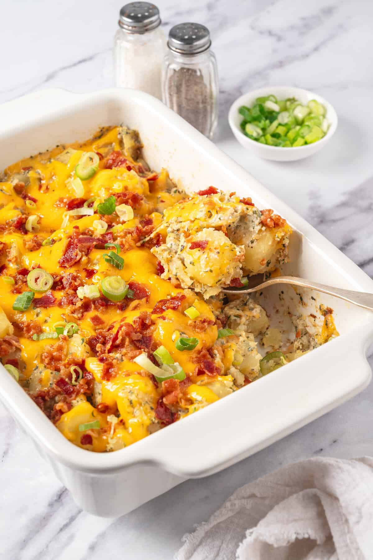 Creamy cauliflower broccoli casserole baked with cheese, bacon, and green onions in a white baking dish. Perfect healthy comfort food recipe for meal prep or family dinners.