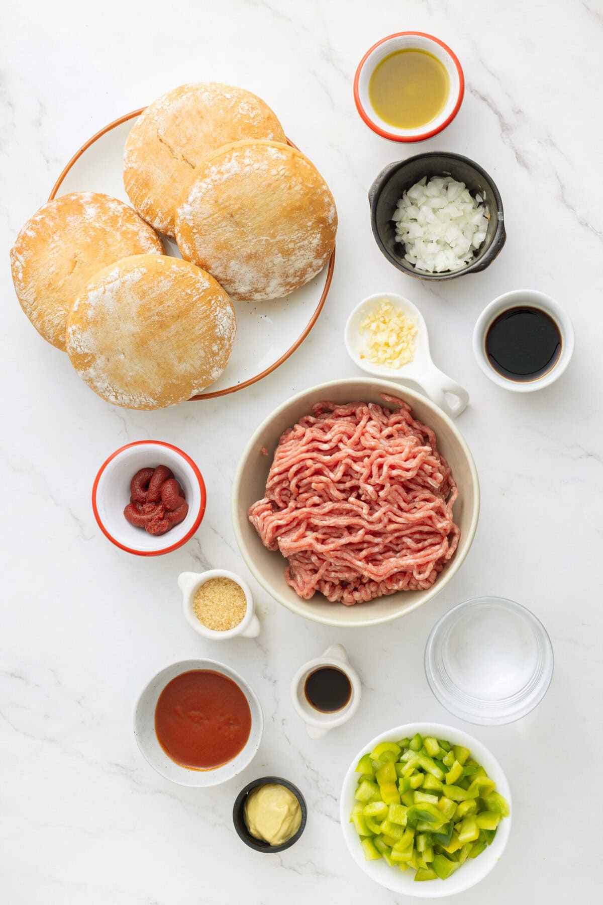 Fresh burger buns, ground beef, chopped onions, celery, pickles, ketchup, mustard, Worcestershire sauce, soy sauce, garlic butter, and seasonings laid out for burger preparation.