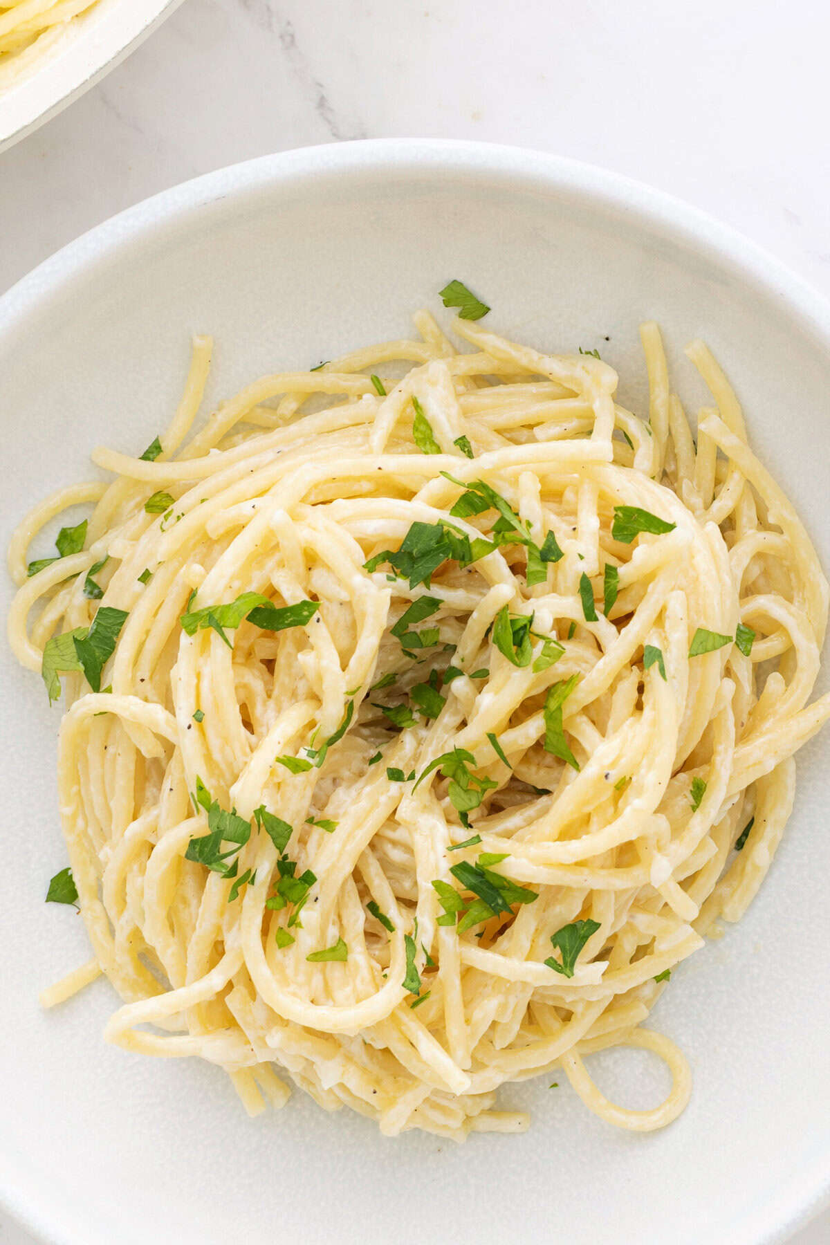 Creamy vegan Alfredo pasta with garlic, herbs, and plant-based sauce on a white plate. Perfect for healthy, gluten-free, and dairy-free meal options from Food Faith Fitness.