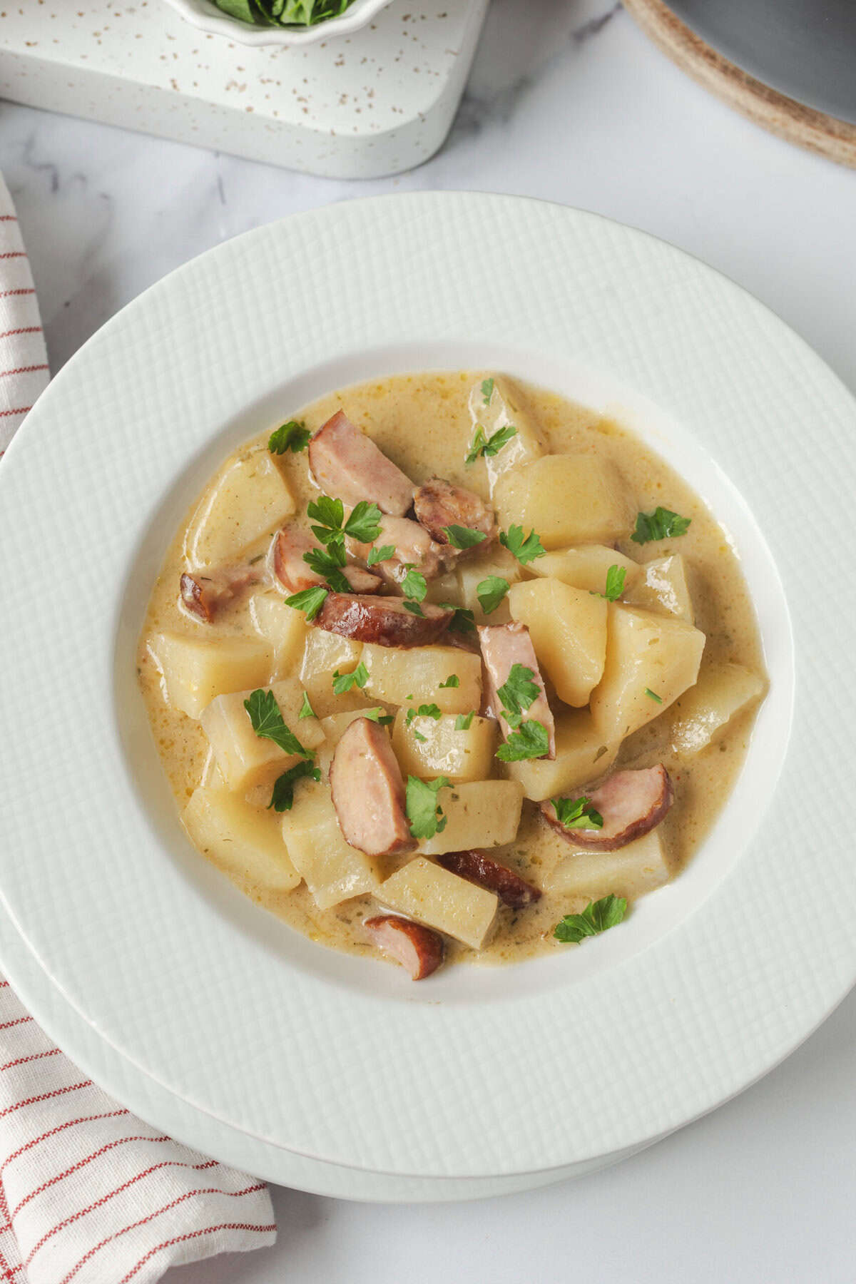 Creamy potato and bacon stew garnished with fresh parsley, served in a white bowl for a comforting and healthy meal. Perfect for clean eating and nutritious weight loss recipes.