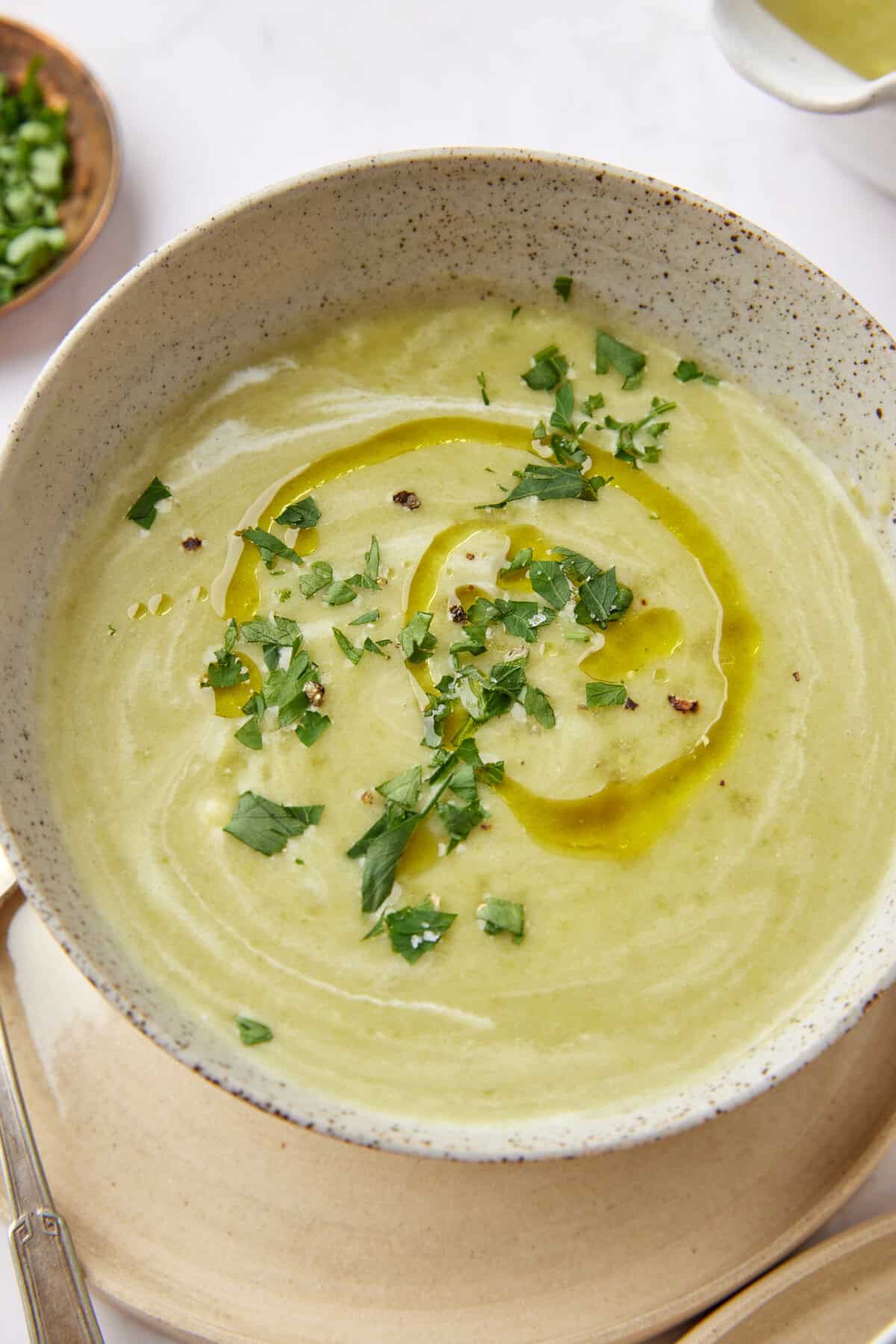 Creamy green vegetable soup garnished with chopped herbs and drizzled with olive oil, served in a rustic bowl for healthy eating and wholesome recipes.