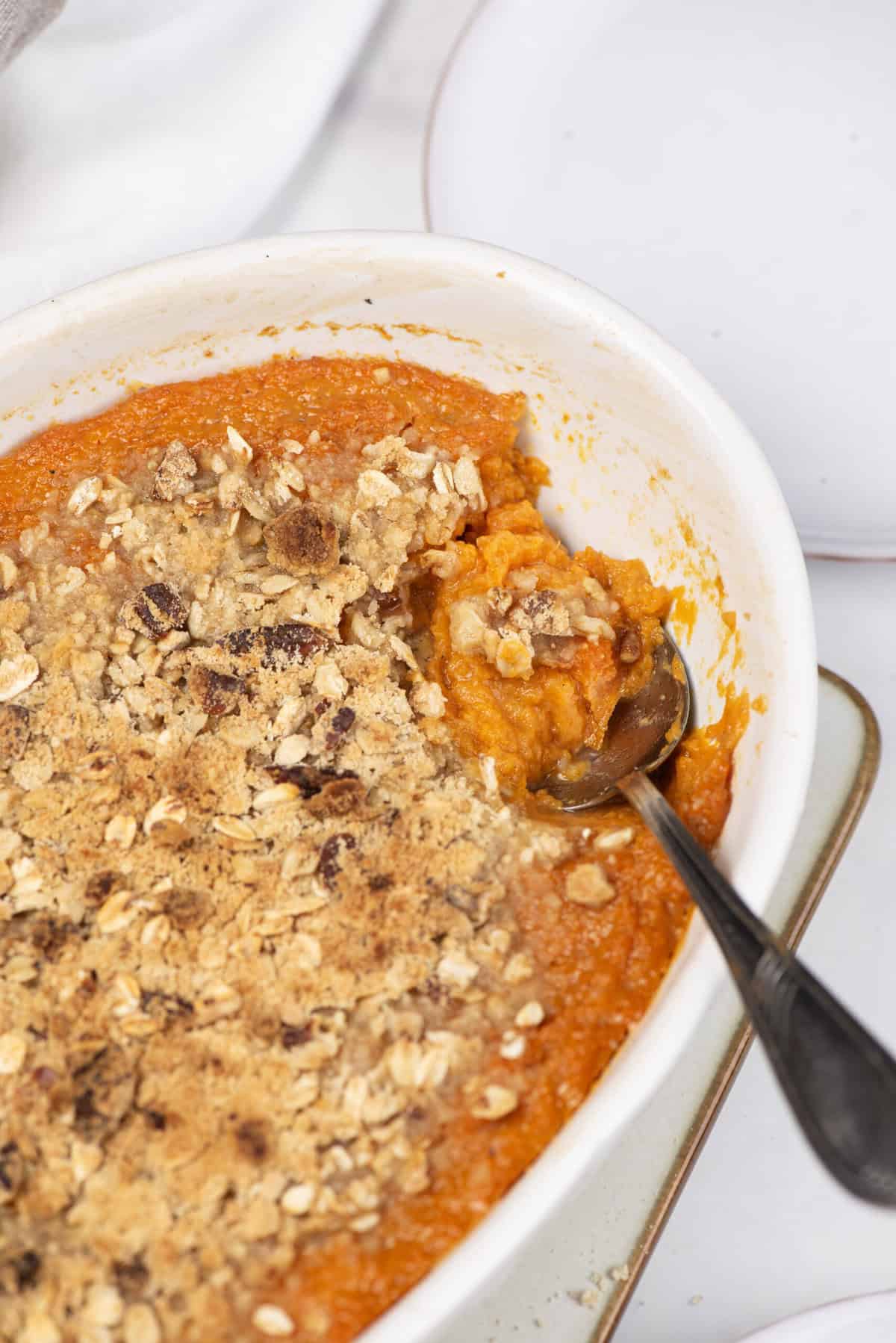 Creamy sweet potato casserole topped with crunchy oat crumble and chopped nuts, perfect for healthy holiday meals and nutritious side dishes.