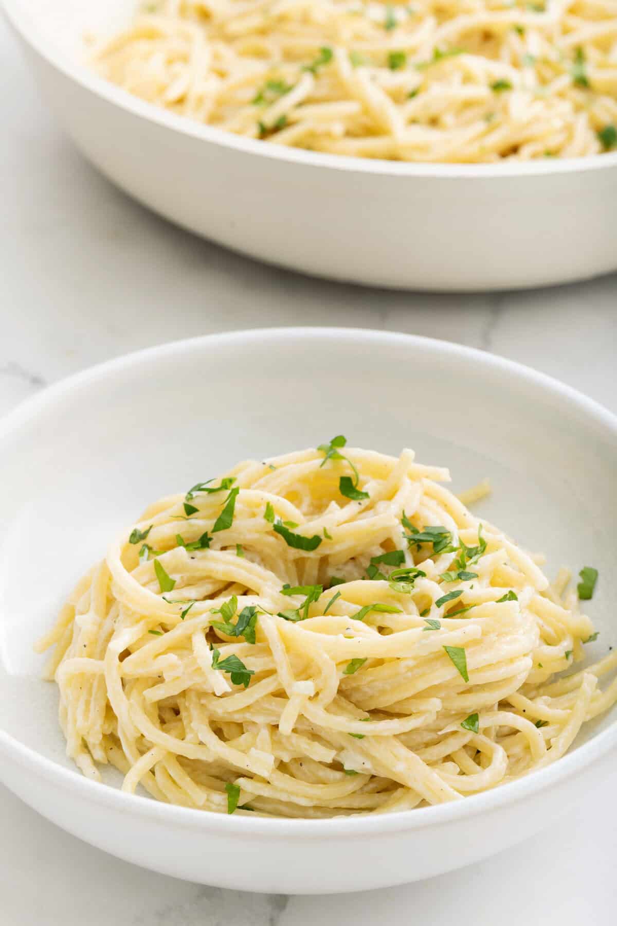 Creamy garlic parmesan pasta garnished with fresh parsley in white bowls, perfect for healthy, delicious meals.