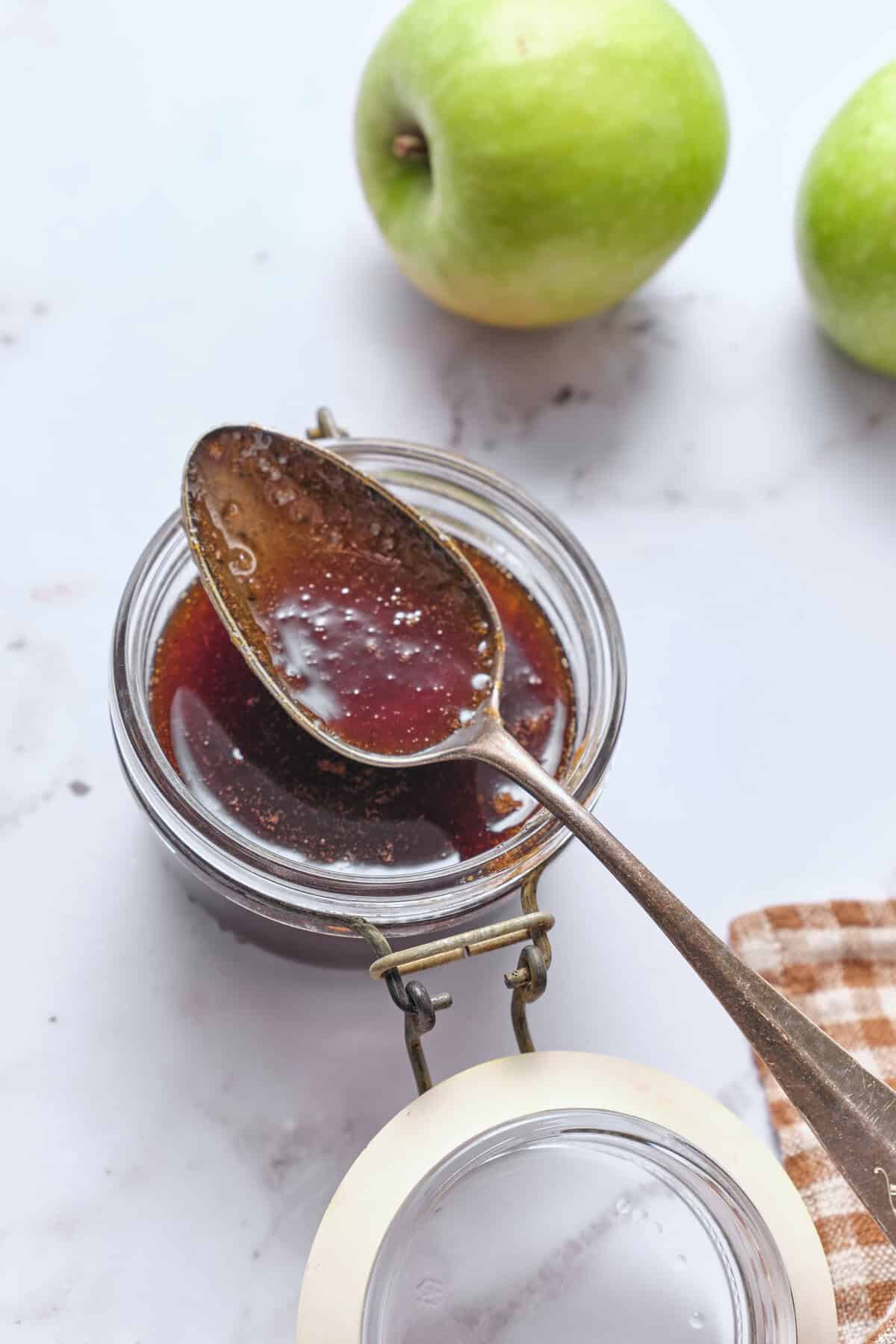 Sweet apple butter spreads in a container with fresh green apples in the background, a healthy recipe for natural fruit canned food, ideal for nutritious breakfast and snacks, ideal for food and fitness enthusiasts.