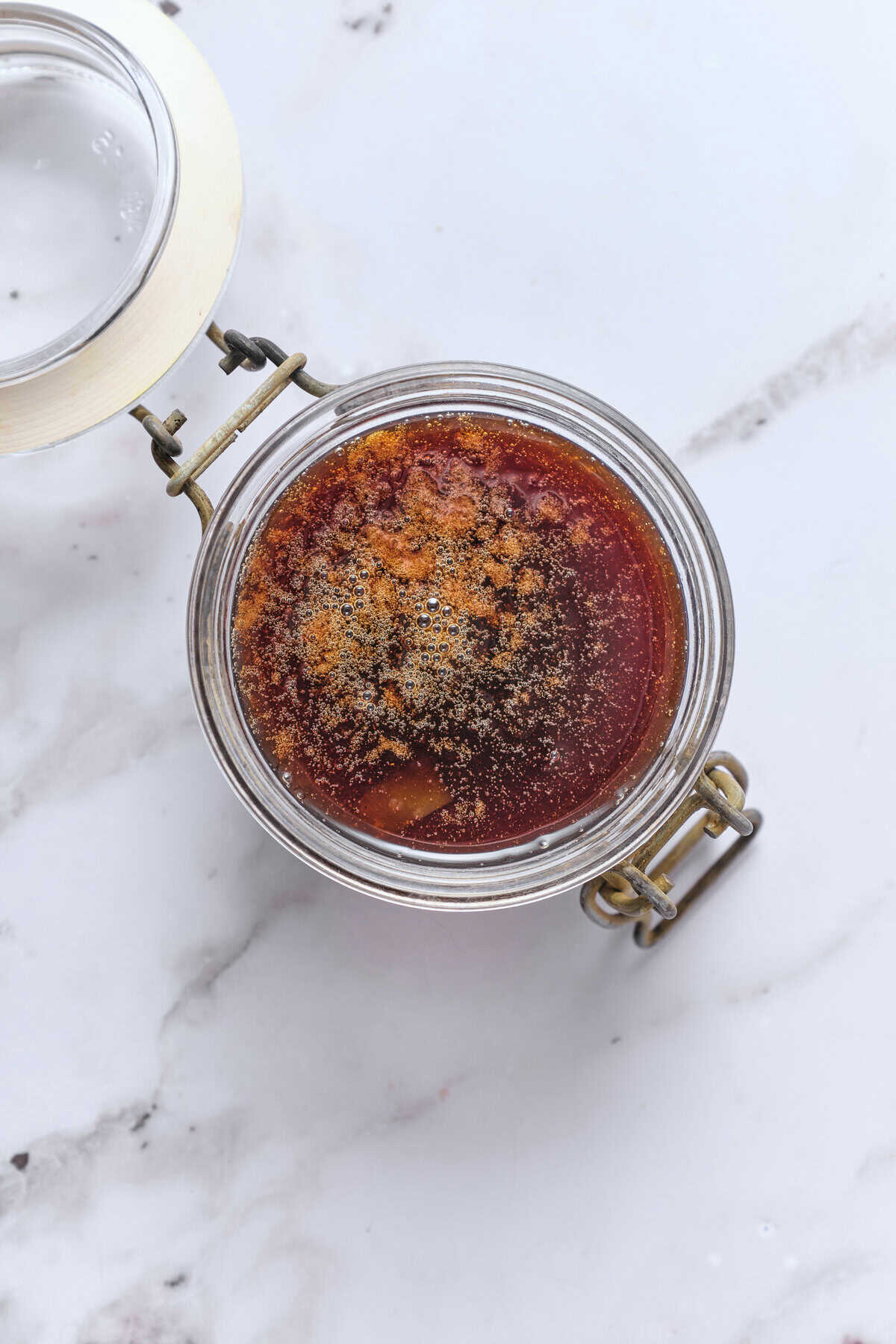 Rich brown broth of cooking in a glass container with lid, preparation of healthy food, homemade broth of soups, fitness faith, nutritious ingredients of cooking.