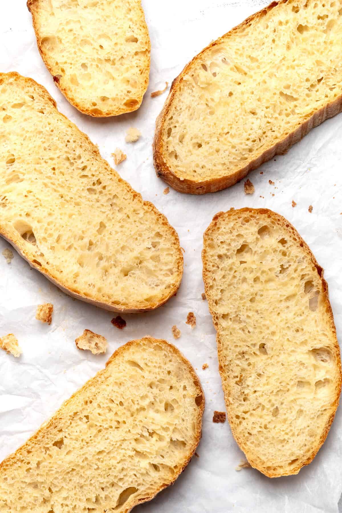 Fluffy homemade garlic bread slices on parchment paper, perfect for healthy eating and meal prep, made with simple ingredients for a delicious side dish.