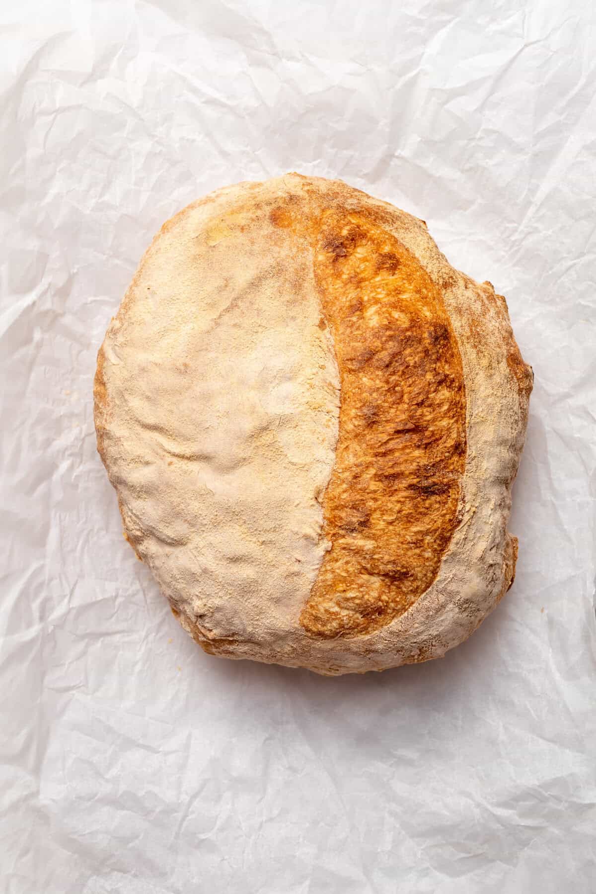 Soft rustic loaf of homemade bread resting on crinkled parchment paper, emphasizing healthy baking recipes and whole grain bread options.