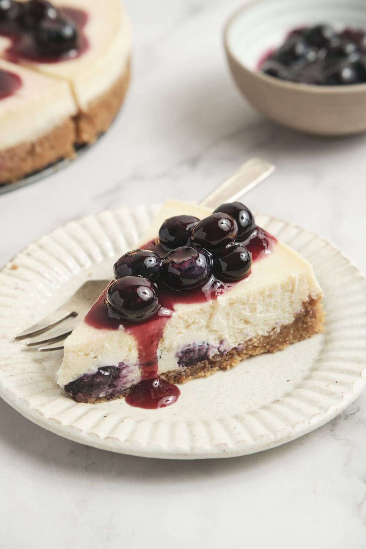 Fresh blueberry cheesecake with a graham cracker crust and berry topping, perfect for healthy dessert recipes and fitness-friendly treats.