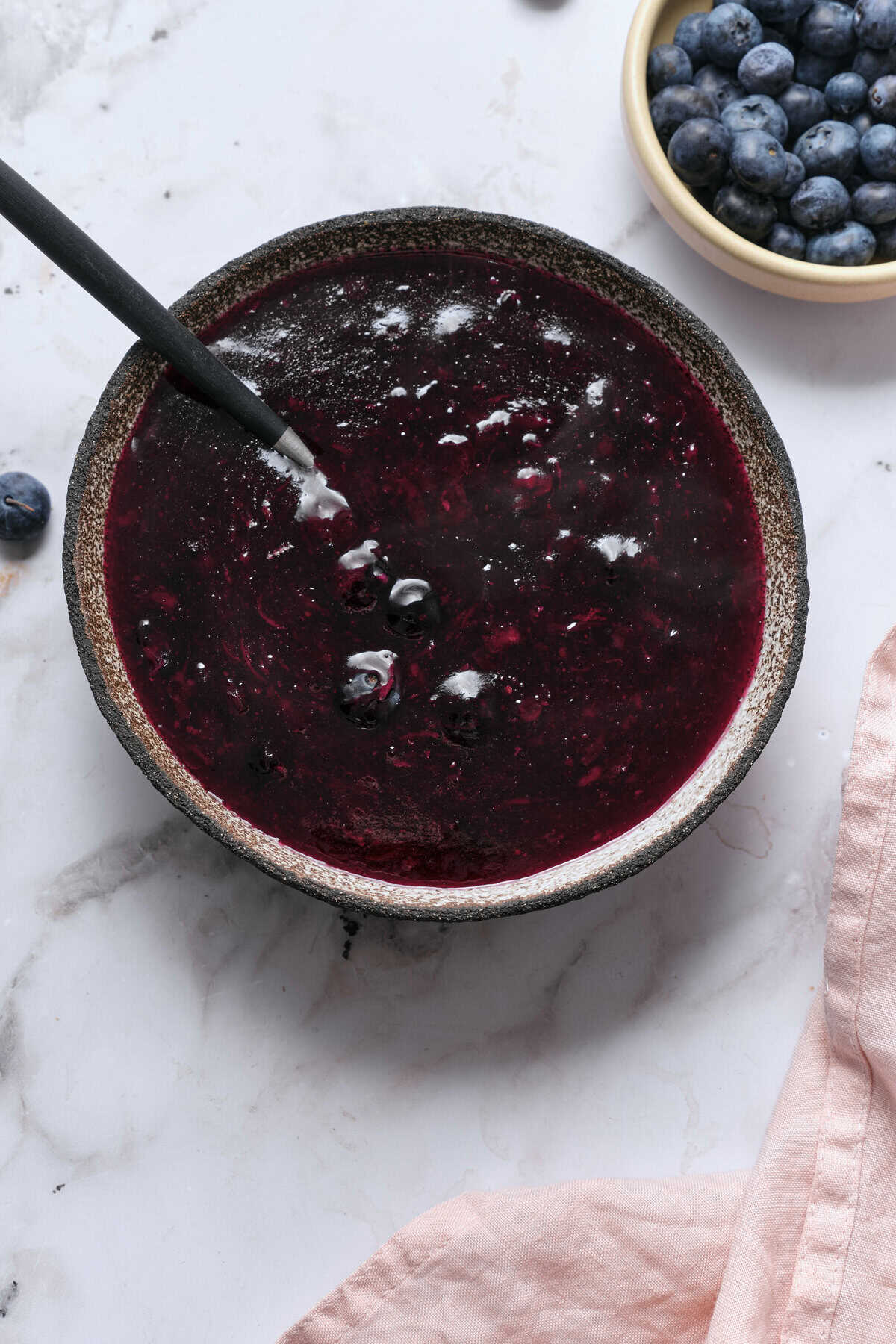 Fresh blueberry compote in a rustic bowl with blueberries in a separate dish, perfect for healthy recipes and nutritious meal toppings.