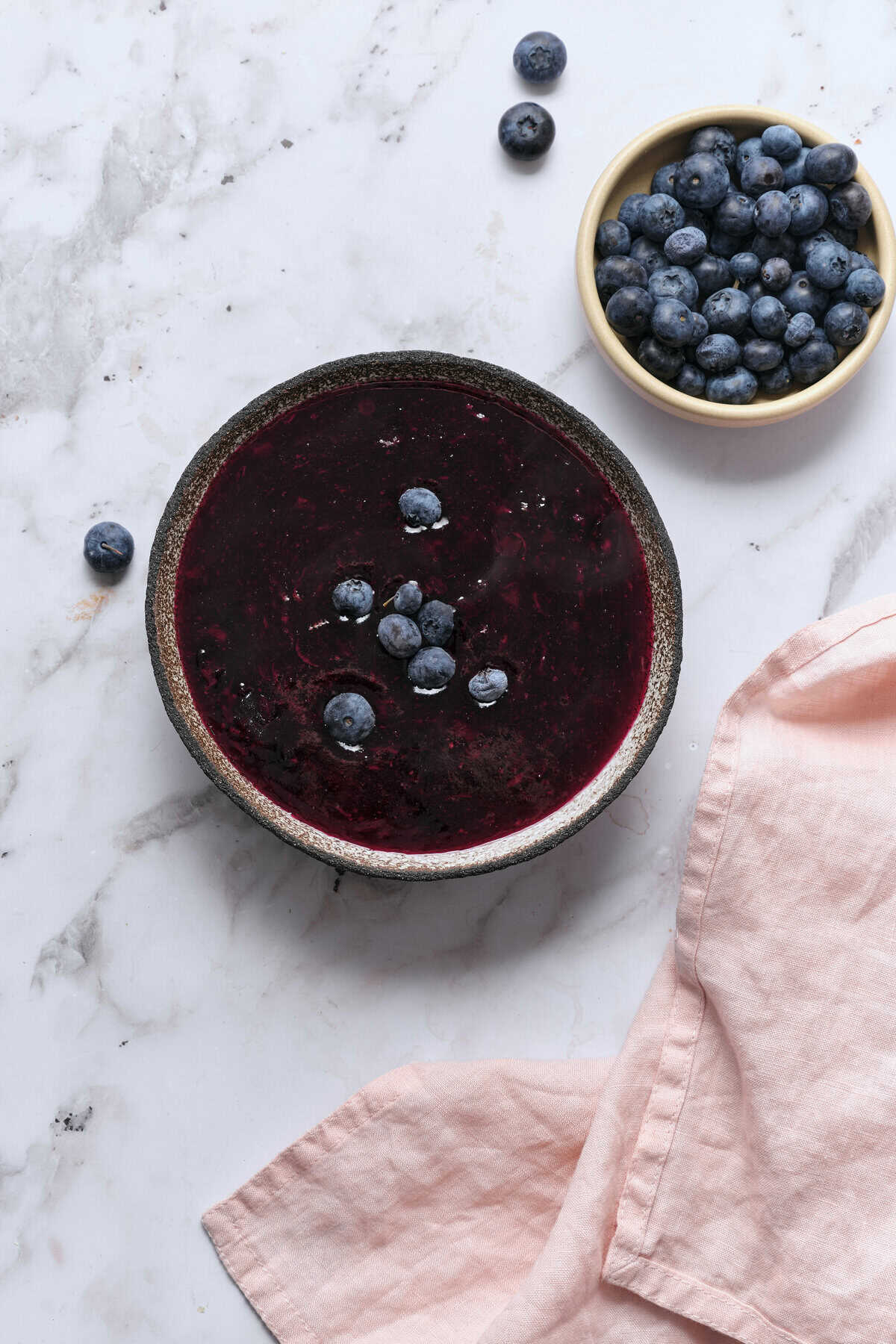 Fresh blueberry smoothie bowl topped with whole blueberries, served on a marble surface for a healthy breakfast or snack. Perfect for nutritious eating and clean eating recipes.