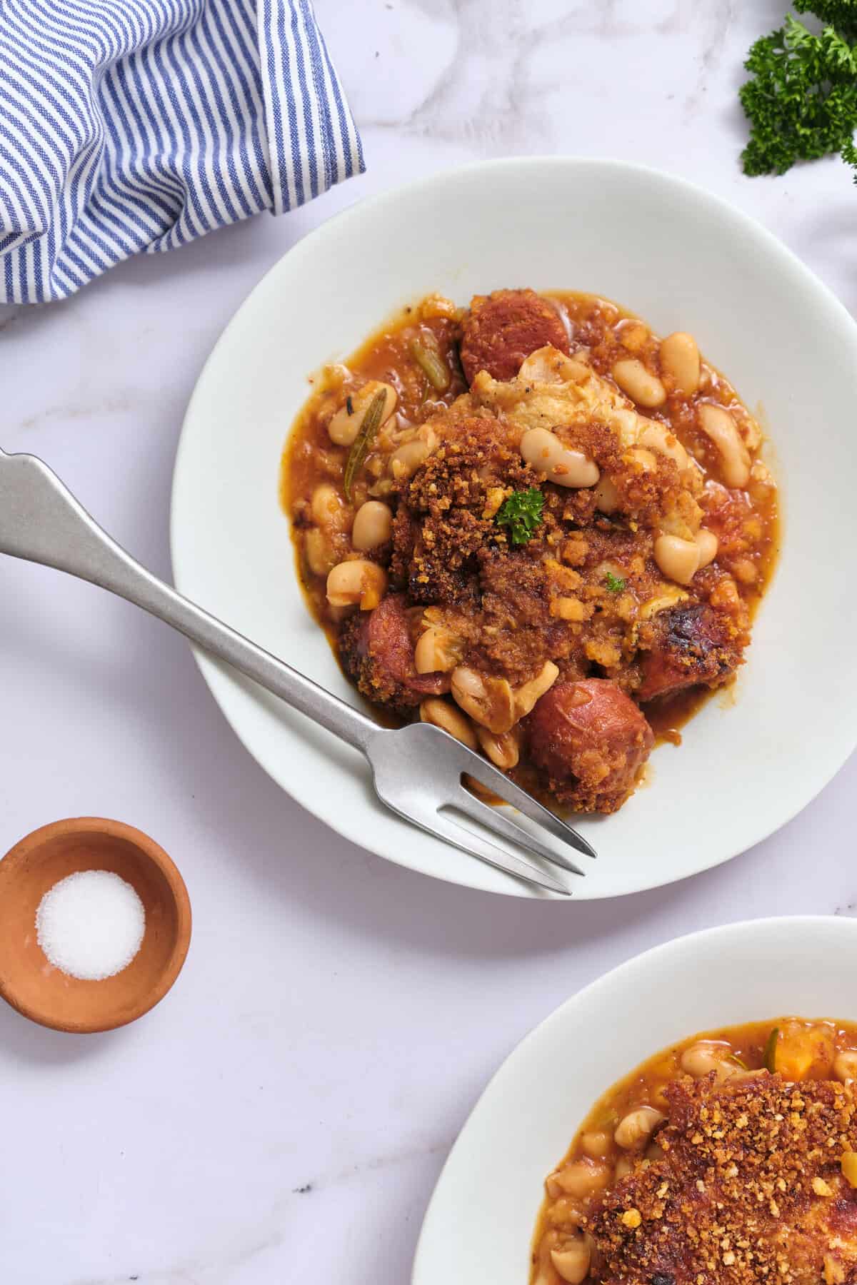 Savory baked ziti with meatballs and white beans in a rich tomato sauce served on a white plate, garnished with parsley. Perfect healthy comfort food recipe for meal prep.