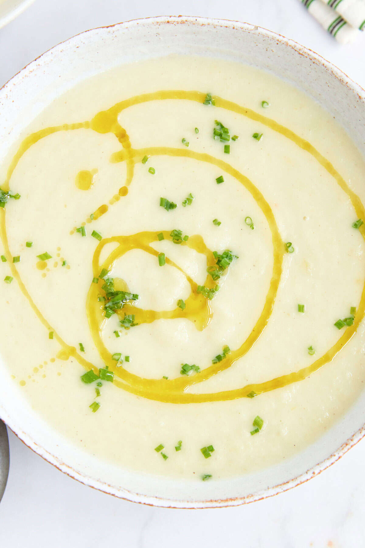 Creamy cauliflower soup garnished with chopped chives and a drizzle of olive oil, perfect for healthy eating and nutritious recipes.