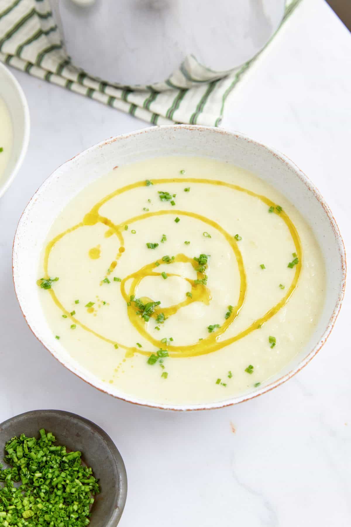 Creamy cauliflower soup with olive oil drizzle and chopped chives, healthy low-calorie vegetarian recipe, perfect for weight loss and nutritious meal planning.