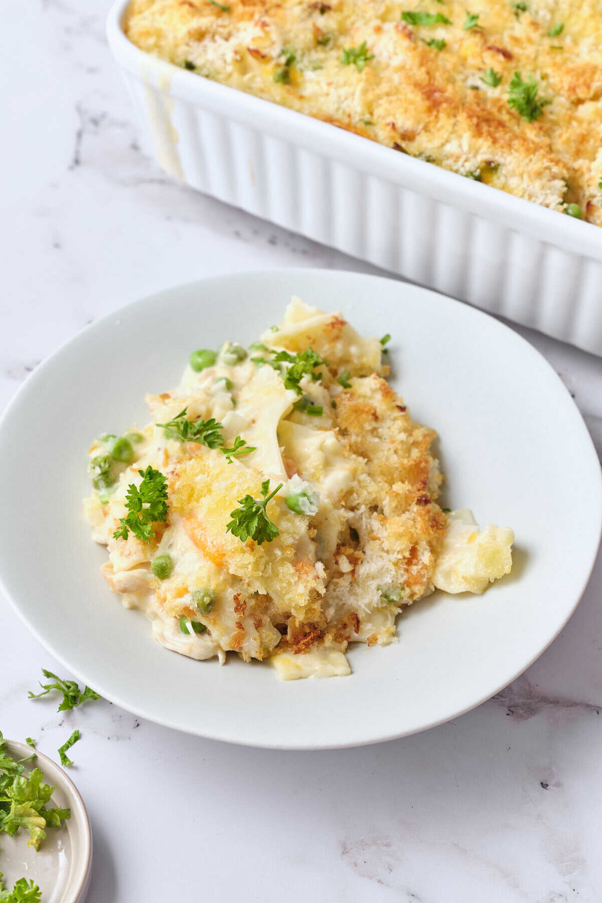 Creamy cauliflower and potato casserole with green peas, topped with crispy breadcrumbs and fresh herbs, perfect for healthy comfort food.
