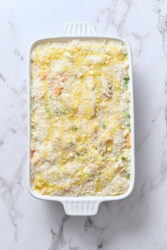 Creamy asparagus and chicken casserole with cheese and breadcrumbs in a white baking dish on marble background.