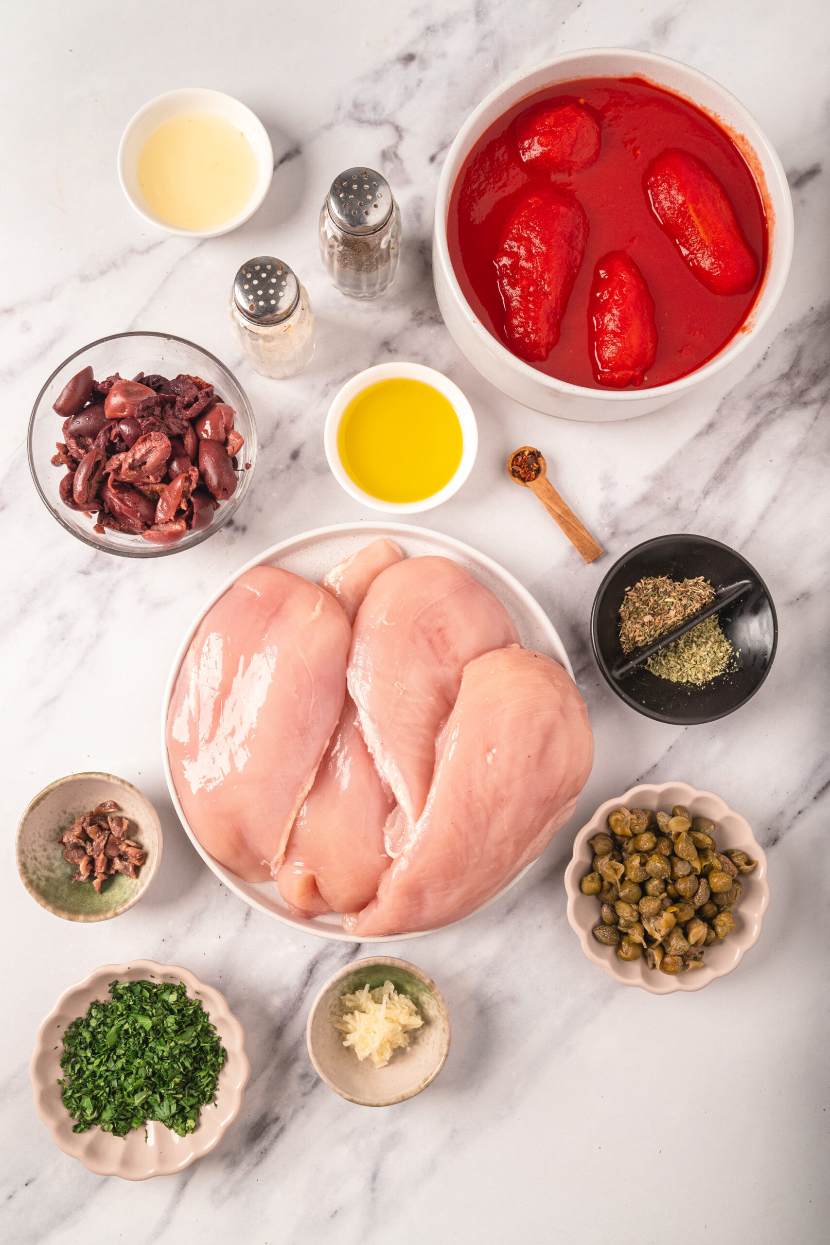 Juice, chicken, herbs, and spices for a healthy chicken breast recipe with tomatoes, olives, and seasonings, perfect for nutritious meal prep and flavorful cooking.