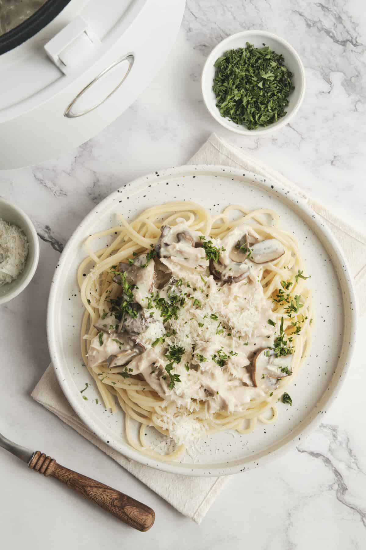 Creamy mushroom and chicken spaghetti pasta featured on a white plate with fresh parsley garnish. Perfect for healthy, balanced meals, utilizing lean protein and vegetables, ideal for food and fitness enthusiasts focusing on nutritious recipes.
