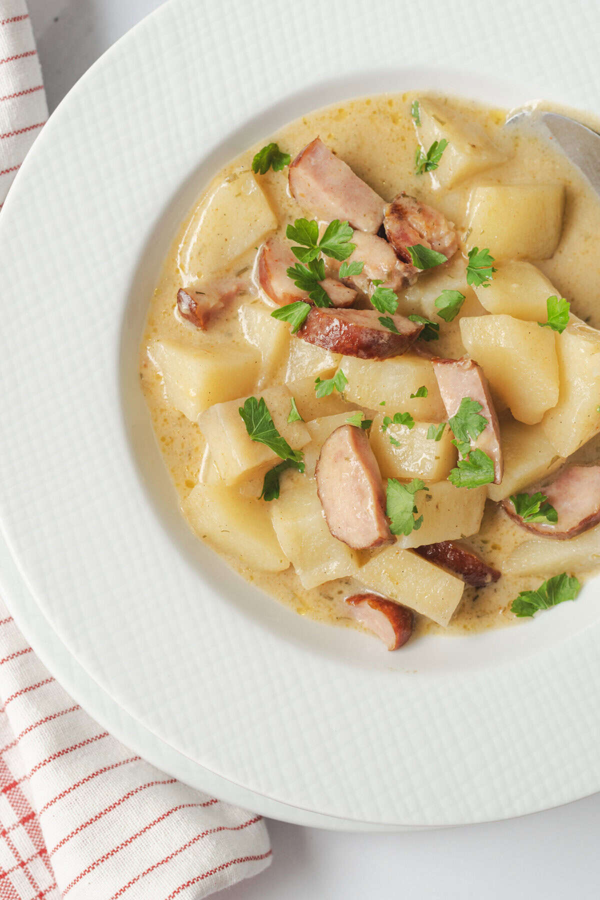 Creamy potato and bacon chowder garnished with fresh parsley on a white plate.