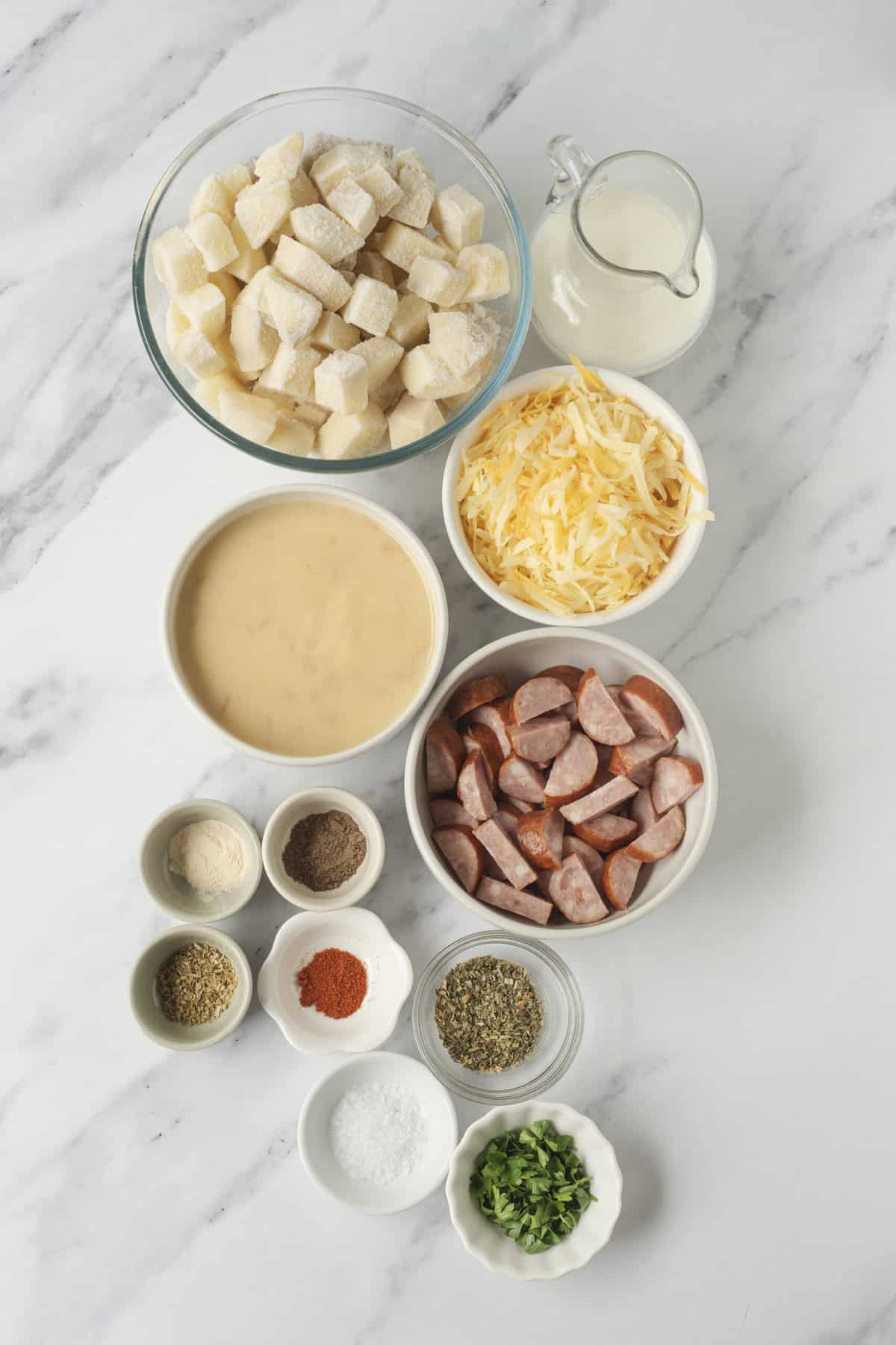 Cream cheese, shredded cheese, diced sausage, cubed potatoes, milk, seasonings, and fresh herbs for a hearty breakfast casserole. Perfect for meal prep and easy breakfast recipes.