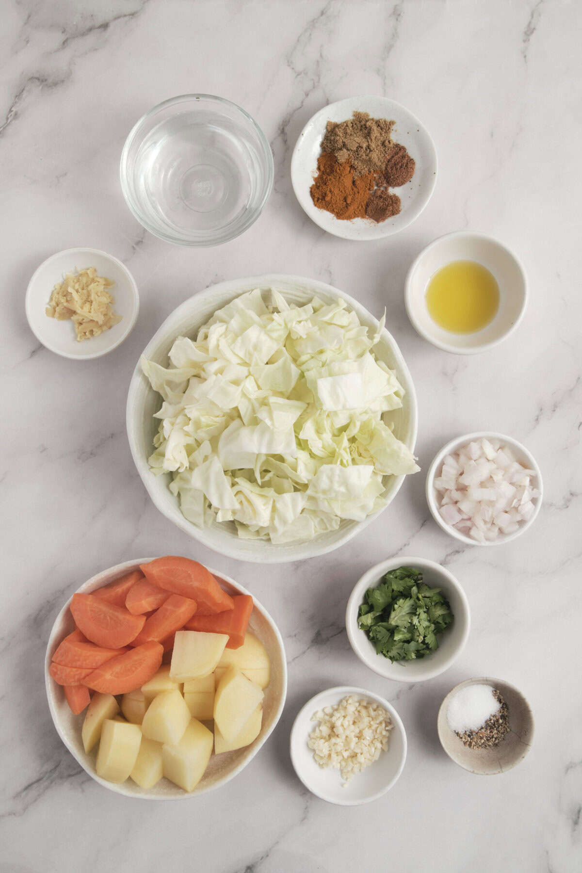 Fresh chopped vegetables and spices on a marble countertop, ideal for healthy meal prep and nutritious recipes.
