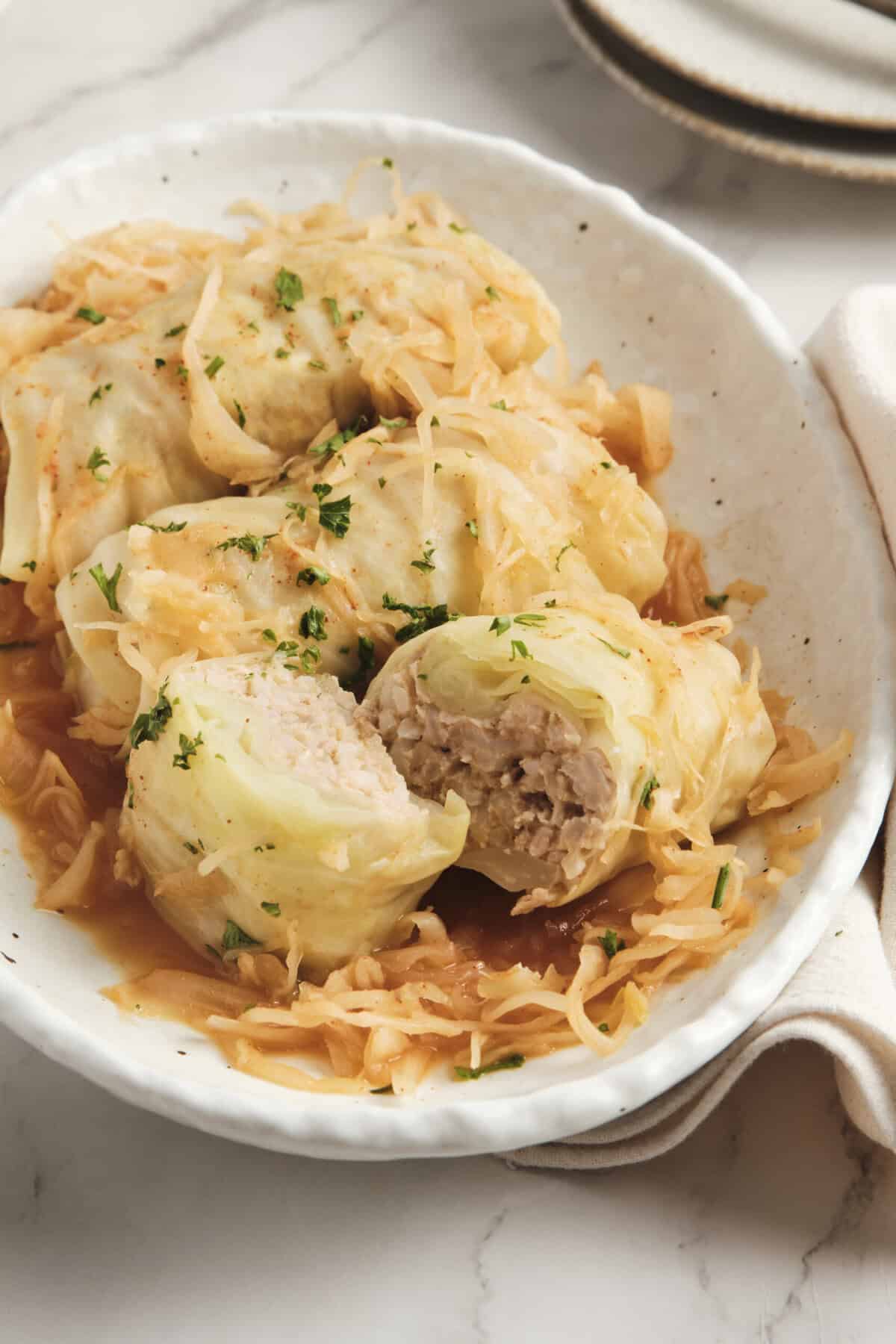 Cream cheese stuffed cabbage rolls in a creamy tomato sauce garnished with fresh herbs, a healthy and flavorful low-carb meal perfect for meal prep or family dinners.