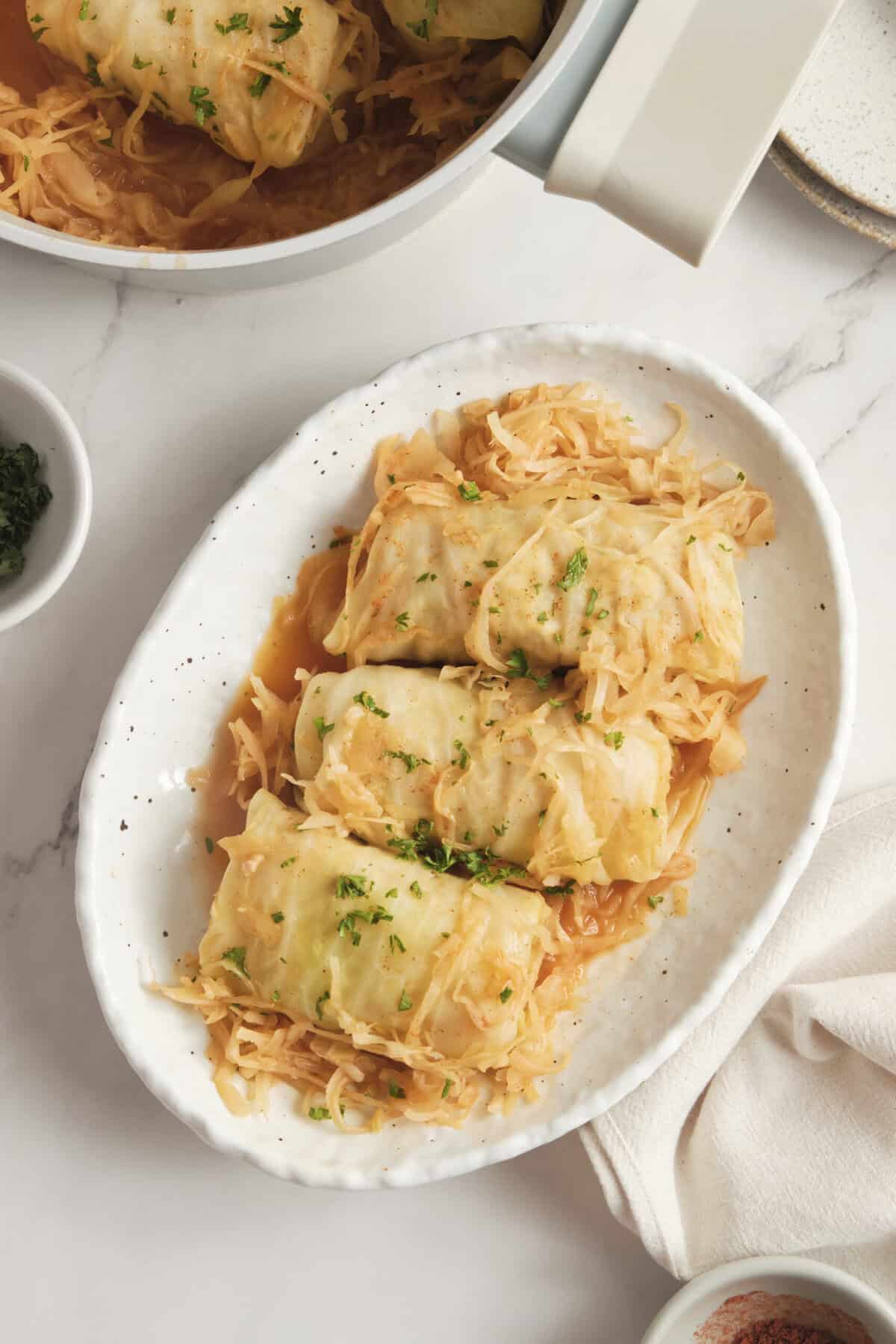 Creamy cabbage roll casserole with sauerkraut and melted cheese served on a white oval platter, healthy comfort food recipe, gluten-free, paleo, and easy dinner idea.