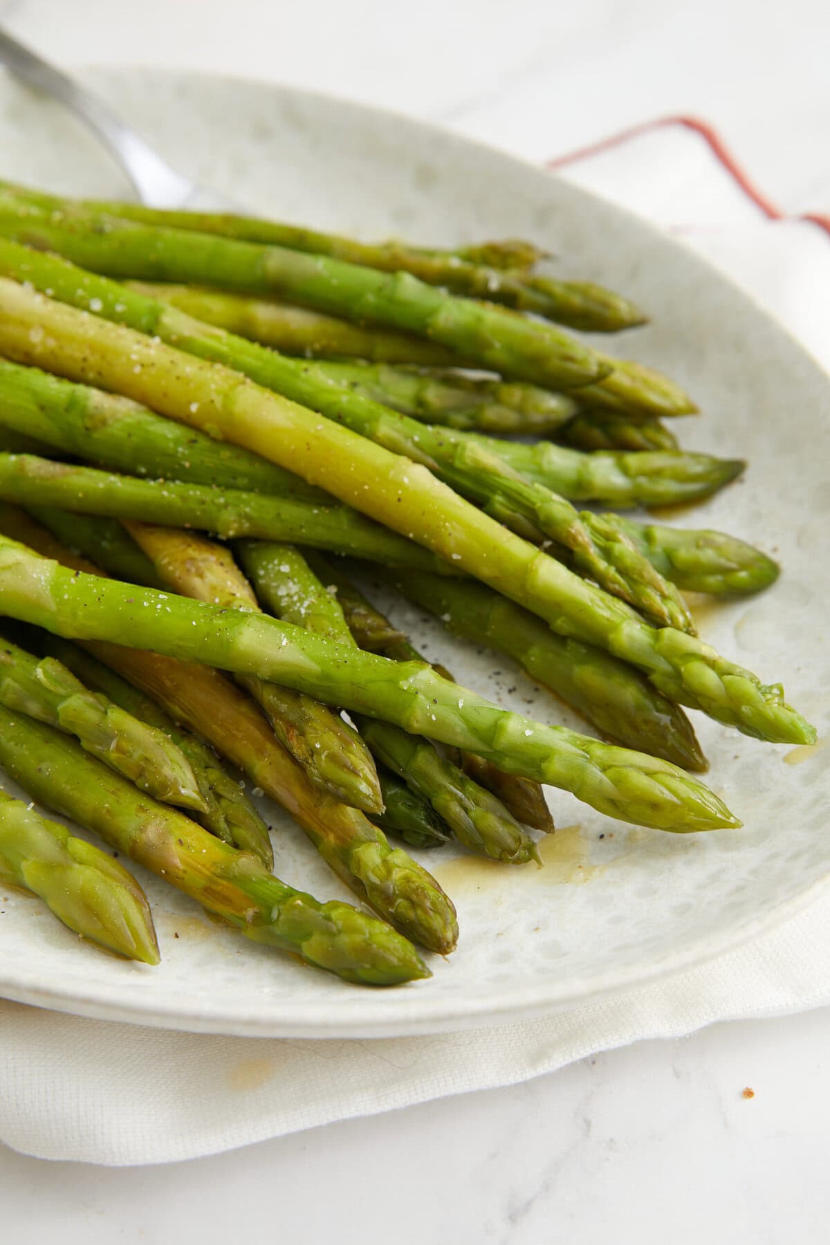 Fresh roasted asparagus spears on a white plate, healthy vegetable side dish for a nutritious meal.
