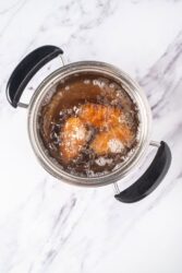 Potato croquettes frying in hot oil until golden brown.