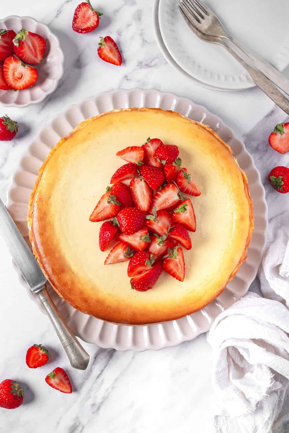 Fresh strawberry cheesecake topped with sliced strawberries on a white plate. Perfect healthy dessert recipe with fresh ingredients, ideal for summer.