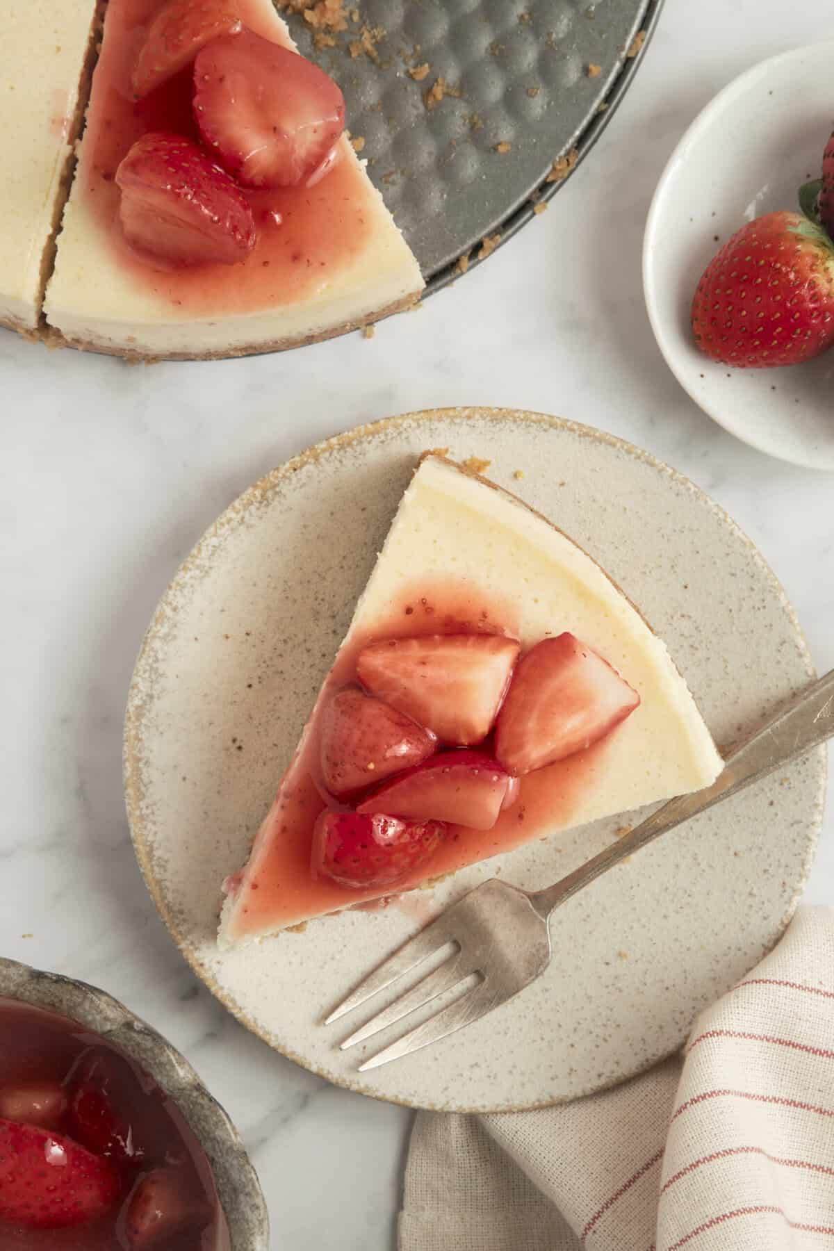 Fresh strawberry cheesecake with fruit topping on a white plate, showcasing a healthy dessert option.