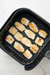 Placing air-fryer halloumi slices in a single layer in the air fryer basket.