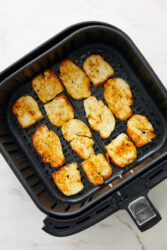 Golden brown air-fried halloumi cheese in an air fryer basket.