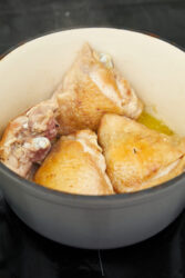 Golden brown chicken pieces searing in a pot for Chicken Scarpariello.