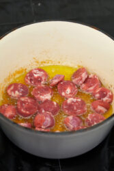 Cooking Italian sausage slices in a pot for chicken scarpariello.