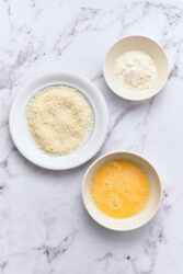 Placing flour, beaten egg, and panko breadcrumbs in bowls for halloumi fries.