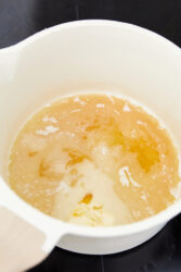 Melting butter and honey in a saucepan for homemade honey-roasted peanuts.