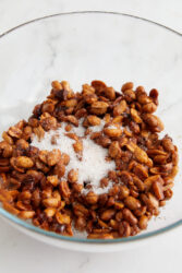 Homemade honey-roasted peanuts in a glass bowl, topped with white sugar.