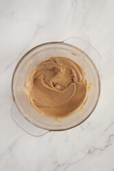 Creamy homemade peanut butter in a clear glass bowl.