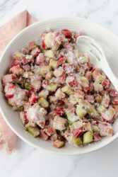 Combining chopped rhubarb and sugar in a bowl for rhubarb jam.