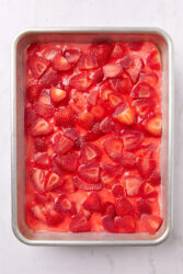 Strawberry pretzel salad with sliced strawberries in a red gelatin layer.