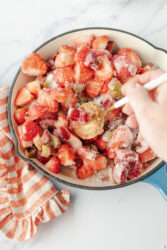 Stirring chopped strawberries, rhubarb, and sugar for strawberry-rhubarb jam.